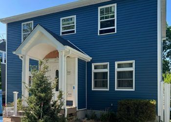 A blue house with white windows and a porch.