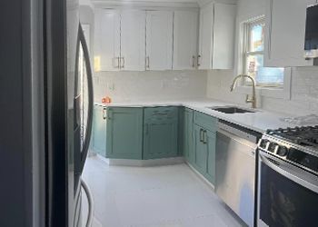 A kitchen with white cabinets , stainless steel appliances , a refrigerator , stove , sink and dishwasher.