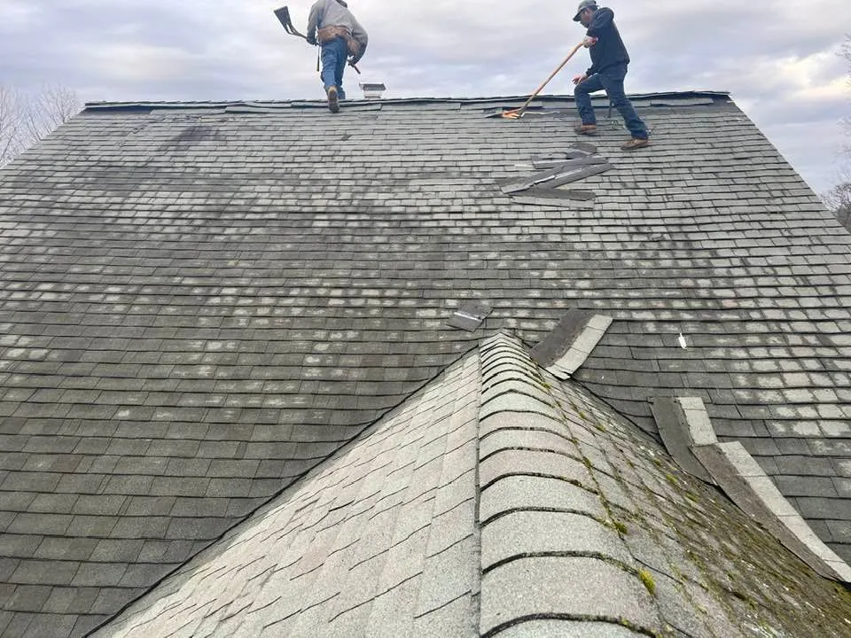 Two men are working on the roof of a house.