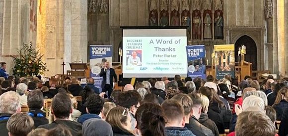 Peter Barker is giving a presentation to a large group of people in St Albans Abbey