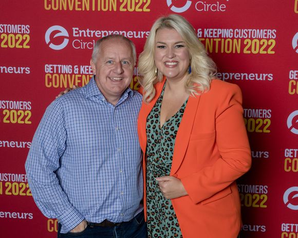 Peter Barker and Sara Davies are posing for a picture in front of a sign that says Entrepreneurs Convention