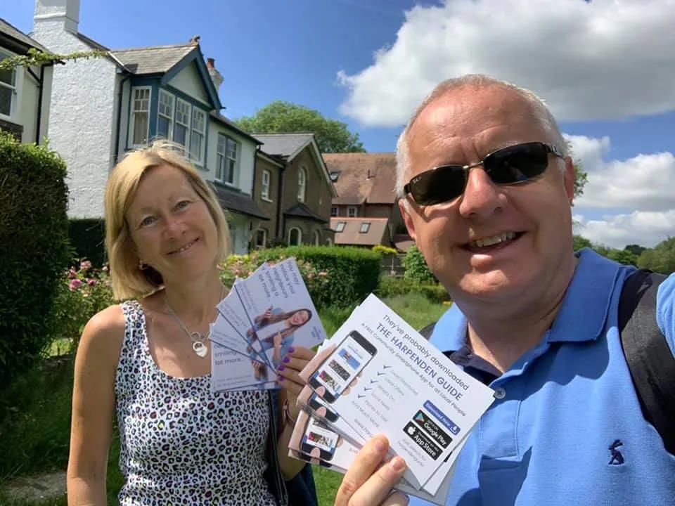 Peter Barker & his wife Kath are standing next to each other holding pamphlets.