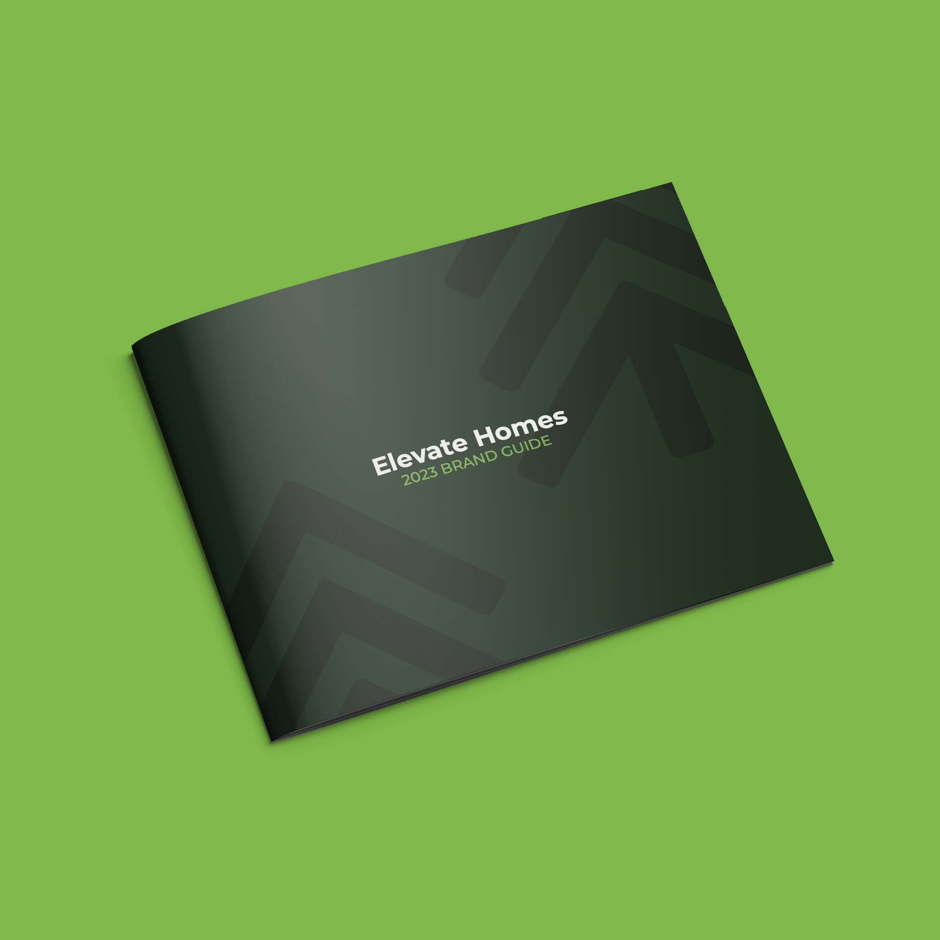 A black brochure for elevate homes is sitting on a green surface.