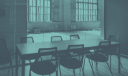 Meeting room with long table and chairs, with large windows in the background.