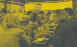 People at a table, dining indoors. Yellow and blue tones dominate.