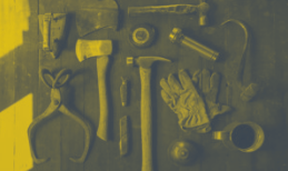 Tools arranged on a dark surface: pliers, axe, hammer, gloves, cup, other tools; tinted yellow.