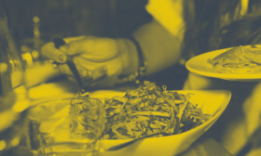 Plates of food being served with a yellow hue. Hand reaching for food.