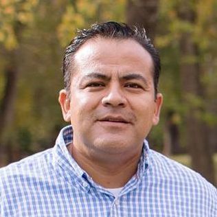 Man smiling with checkered shirt outside