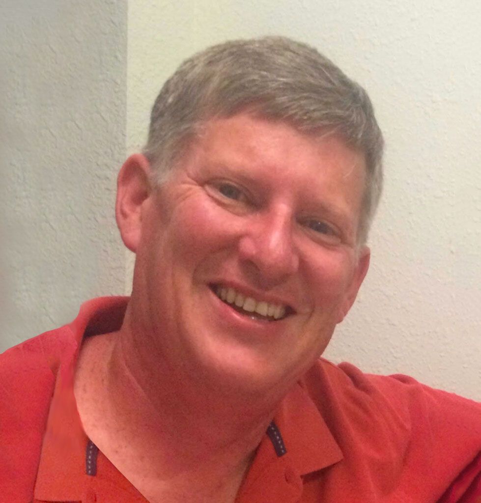 Man in red shirt smiling at camera