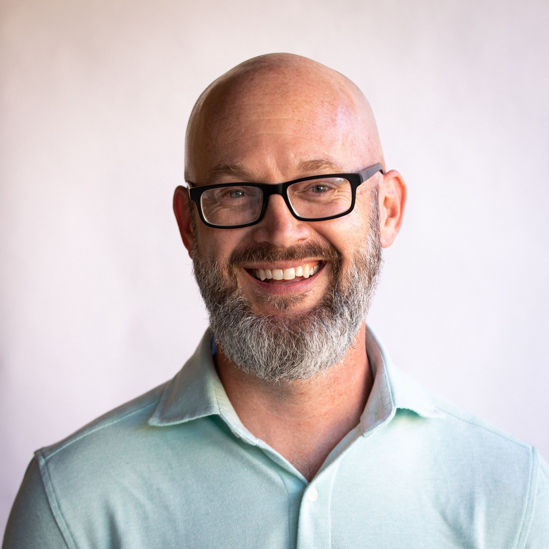Man in glasses in blue shirt smiling at camera