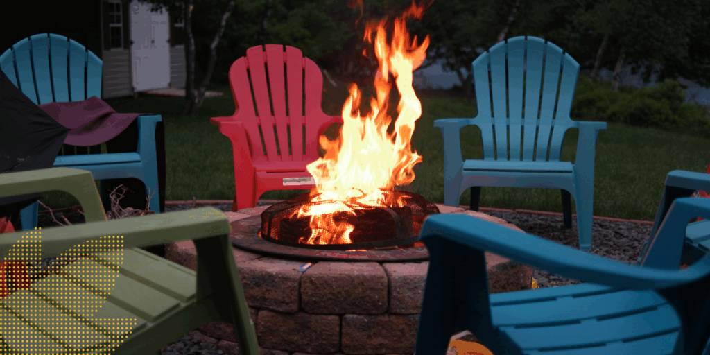 Fire pit with brightly burning flames, surrounded by colorful Adirondack chairs.