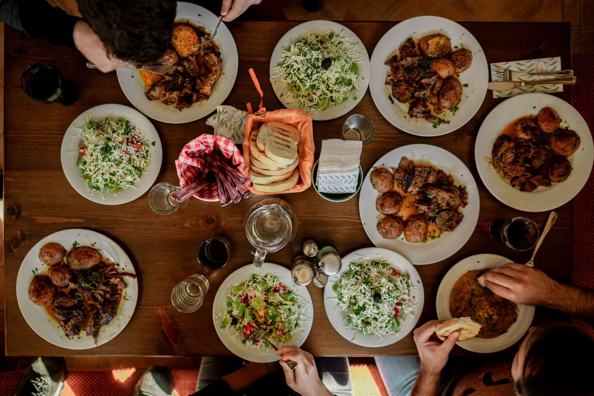 People gathered at a buffet table with food, balloons, and a large window in the background.