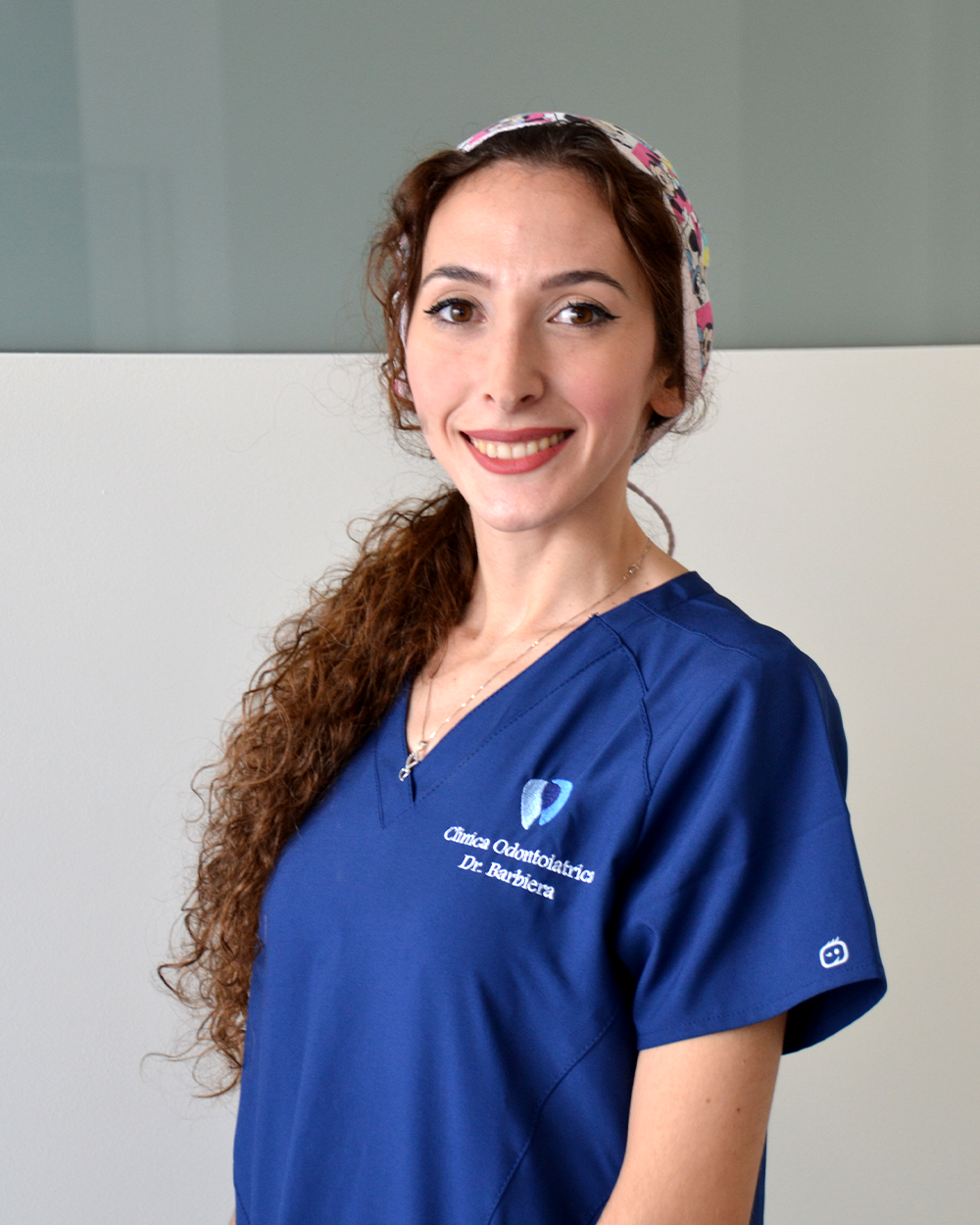 Un uomo in camice bianco sorride con le braccia incrociate.