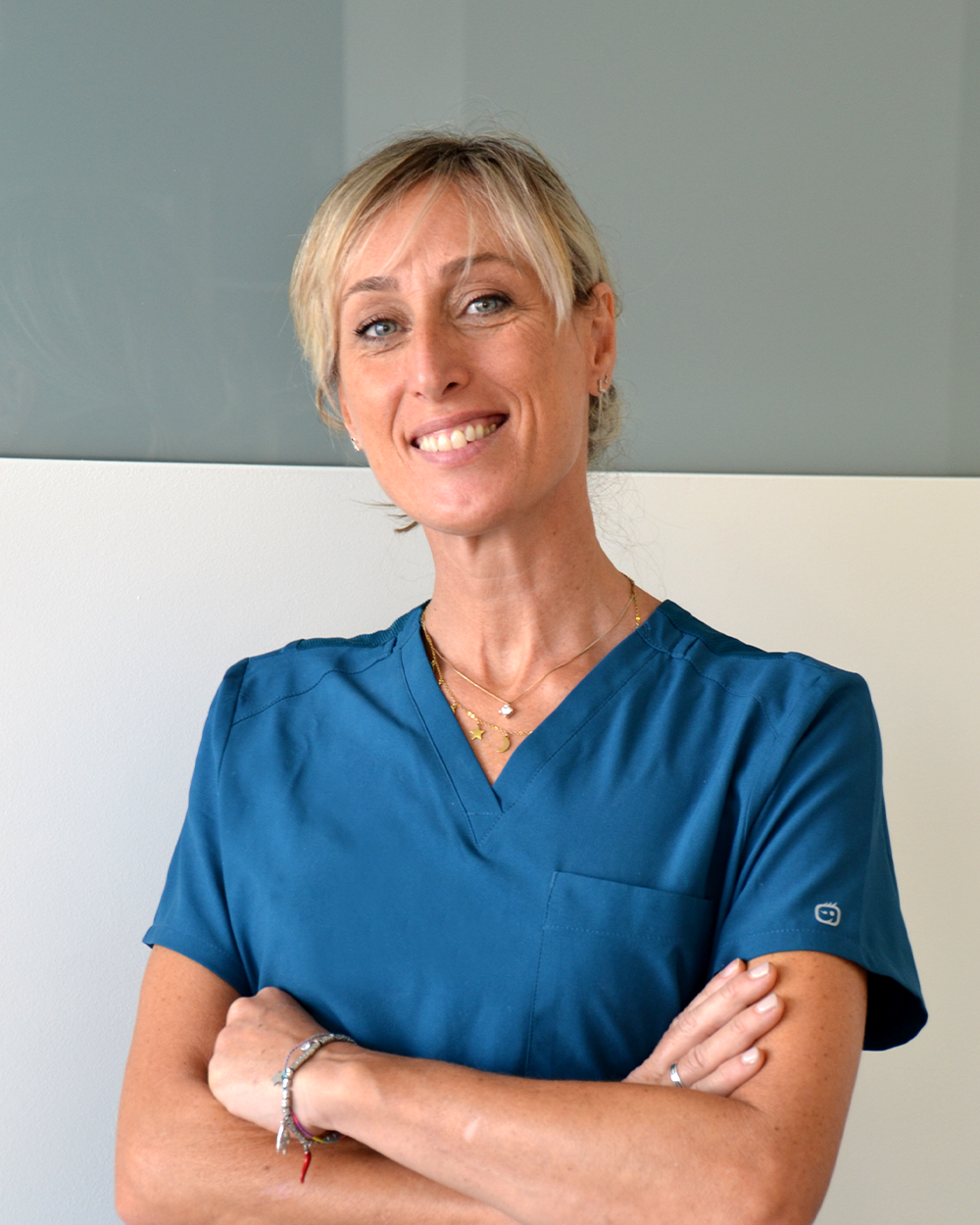 Un uomo in camice bianco sorride con le braccia incrociate.