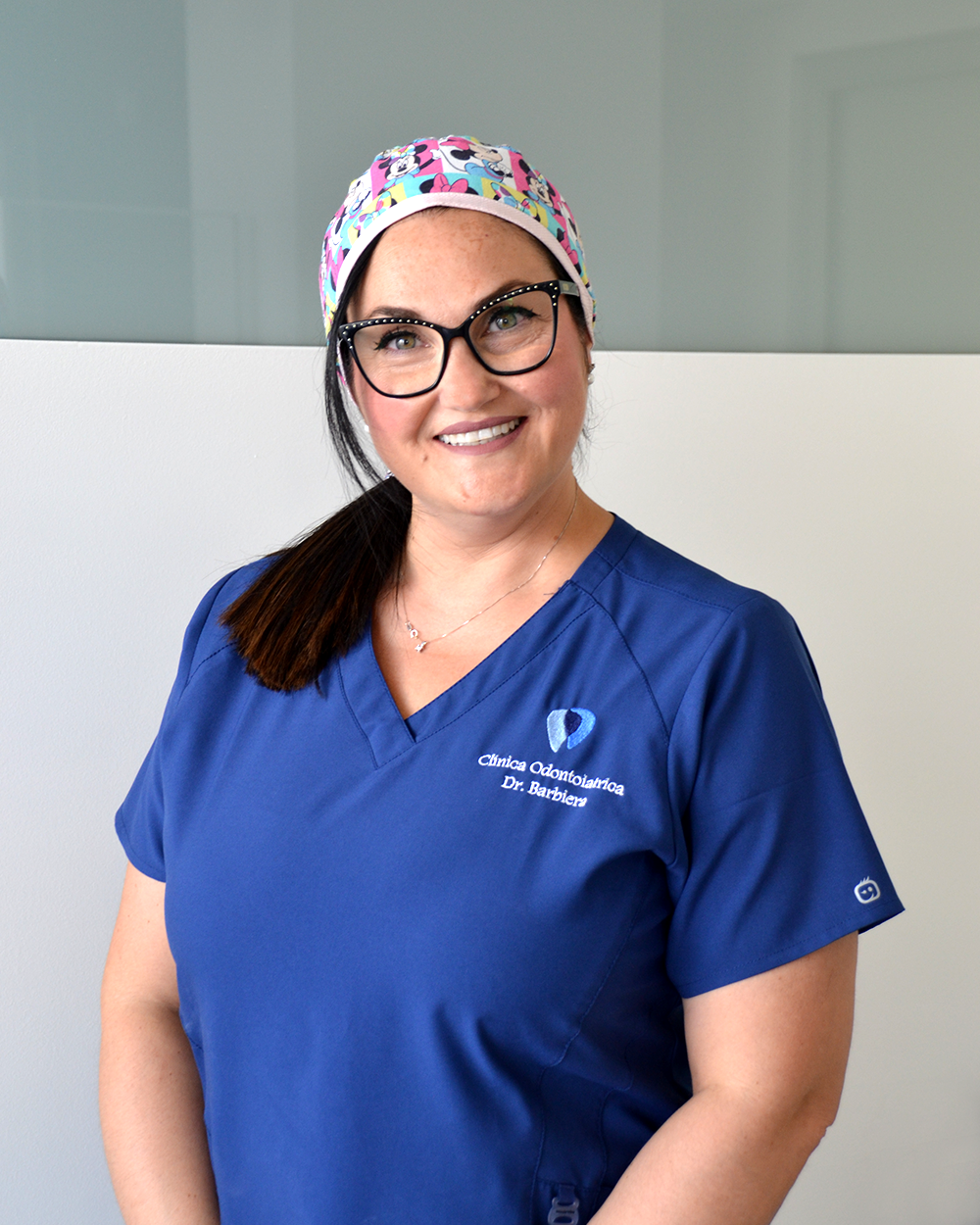 Un uomo in camice bianco sorride con le braccia incrociate.