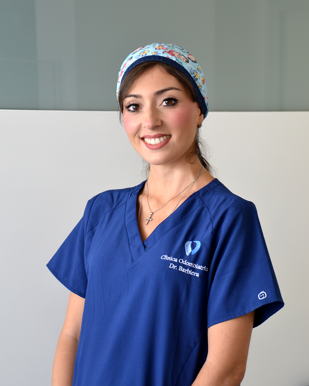 Un uomo in camice bianco sorride con le braccia incrociate.