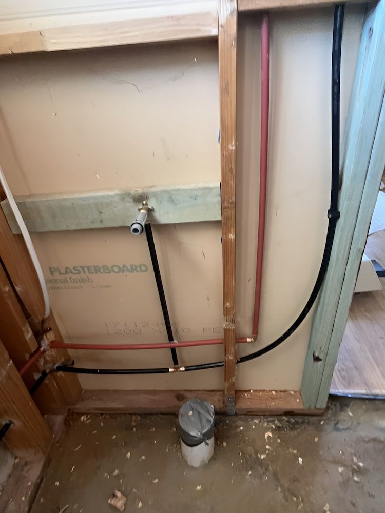 Plumbing Pipes Exposed in a Wall. Red and Black Pipes — Primed Plumbing & Gasfitting in Eglinton, NSW