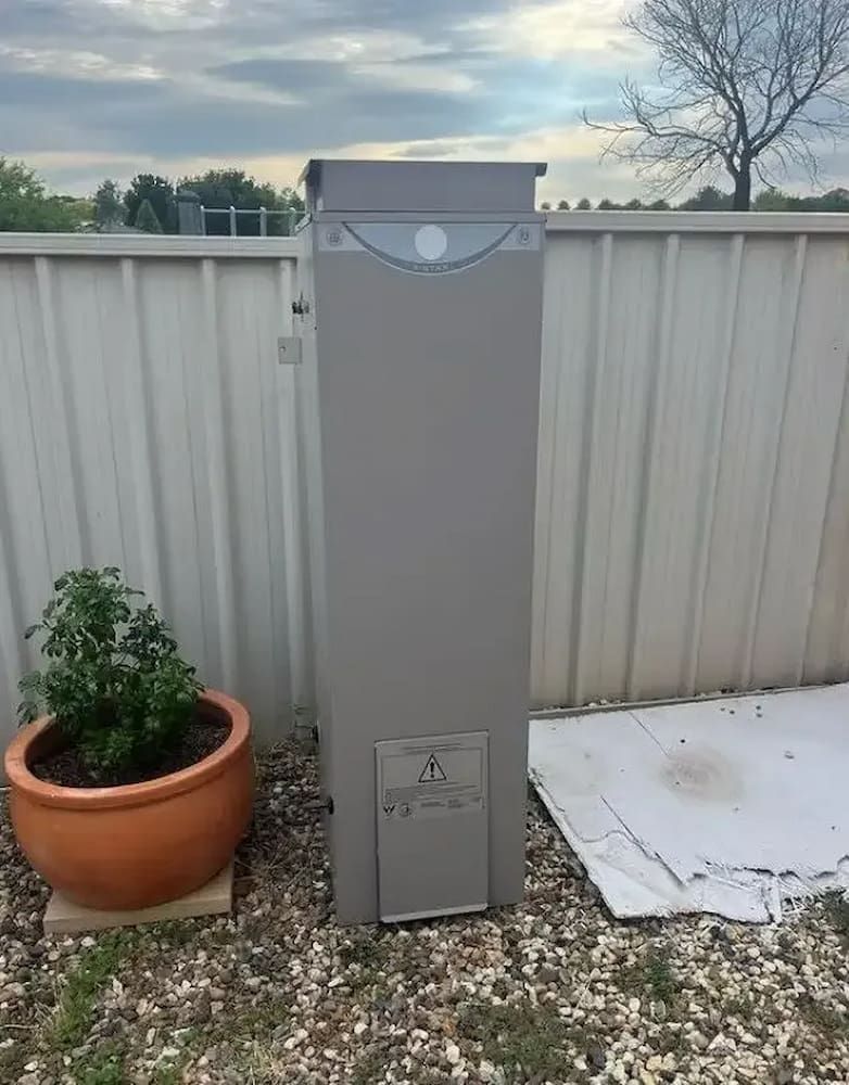 Tall Gray Outdoor Appliance Against a White Fence — Primed Plumbing & Gasfitting in Eglinton, NSW