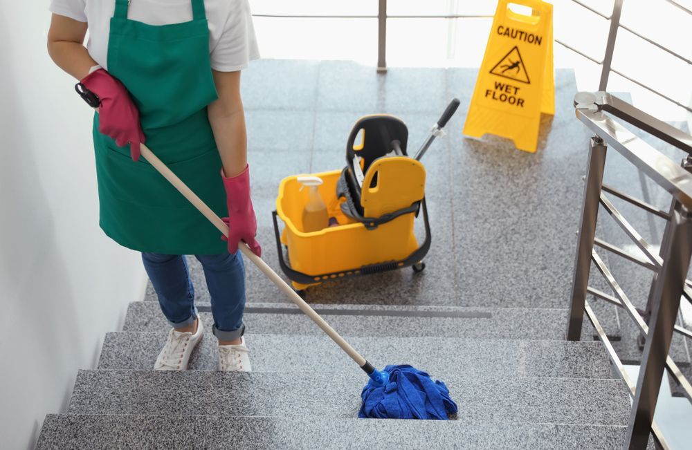 A woman is cleaning a wet floor with a mop.