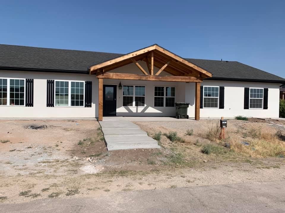 A large white house with black shutters and a wooden porch.
