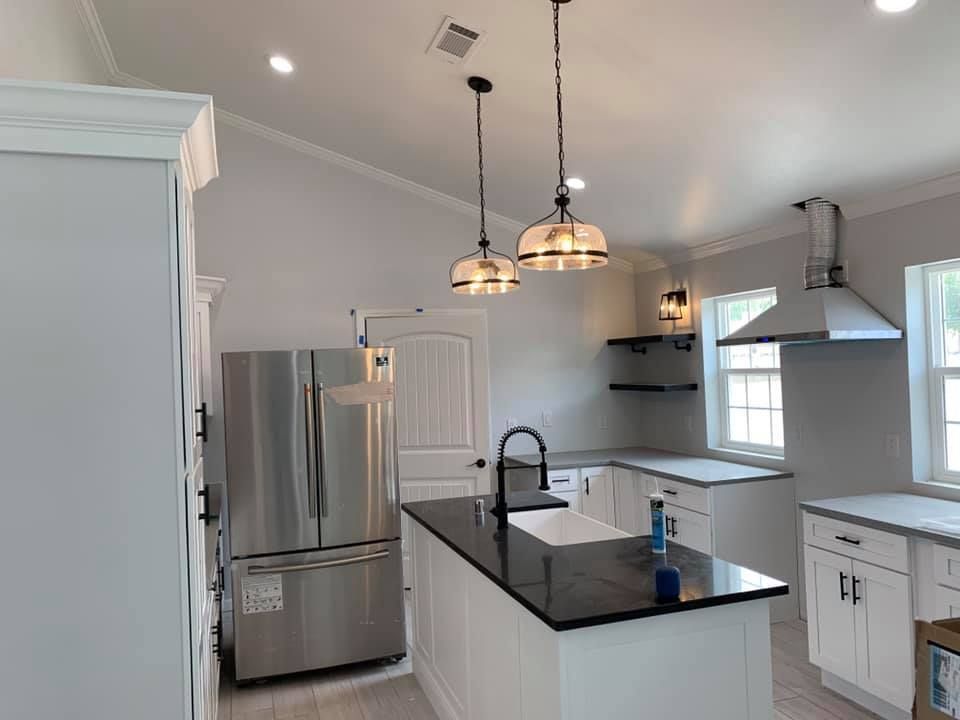A kitchen with stainless steel appliances , white cabinets , a large island and a refrigerator.