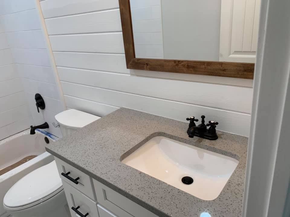 A bathroom with a sink , toilet , bathtub and mirror.