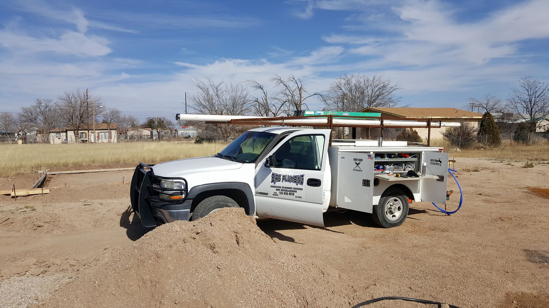 A white truck is parked in a dirt field.