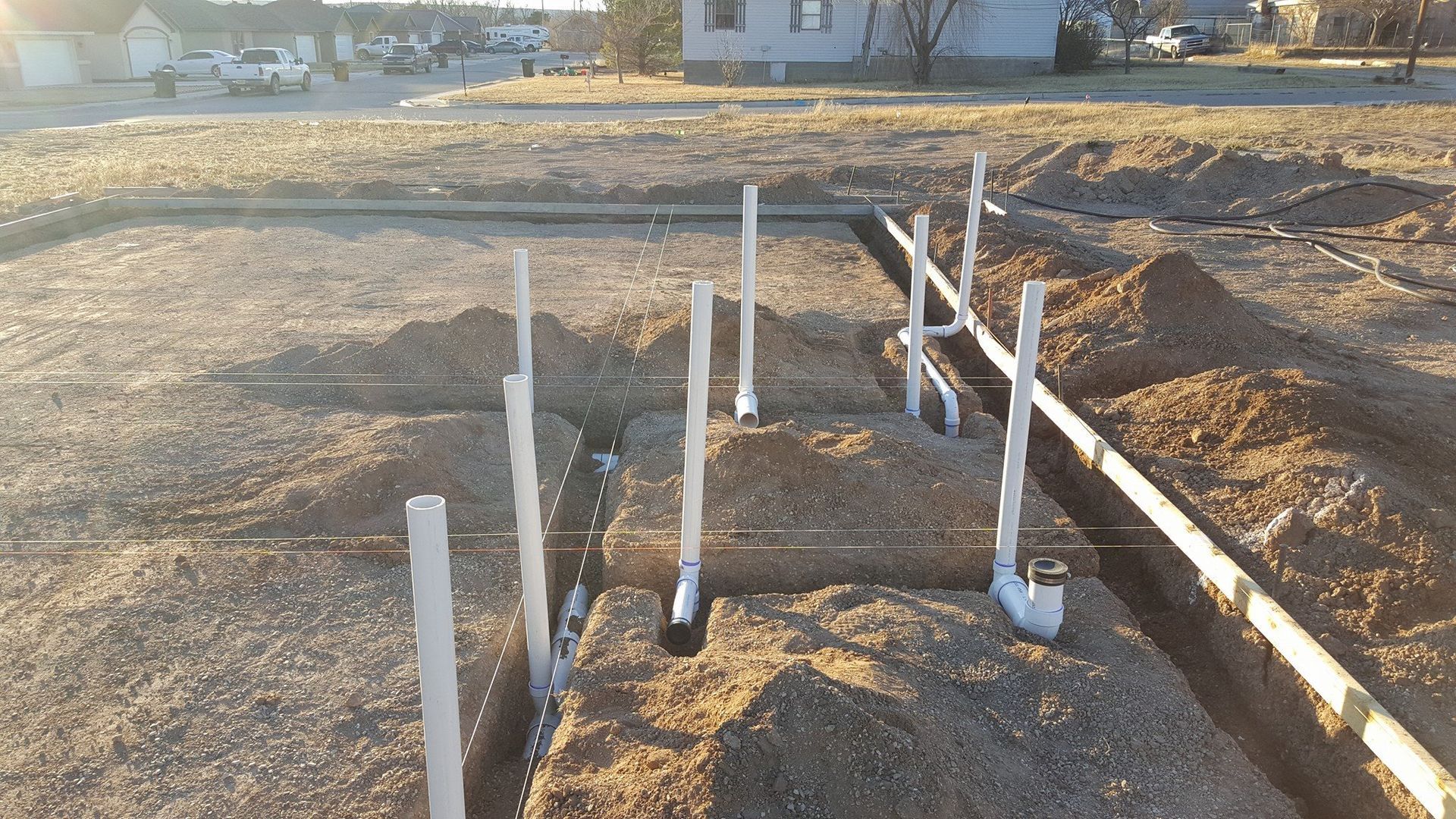 A construction site with a lot of pipes in the dirt.