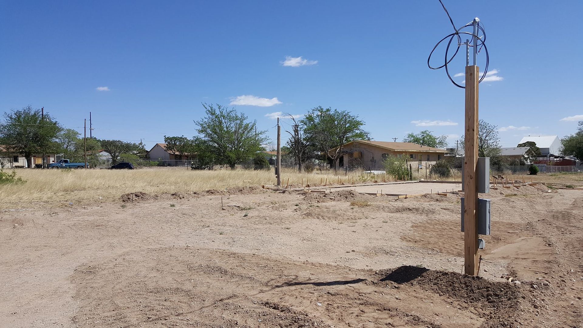 A wooden post in the middle of a dirt field