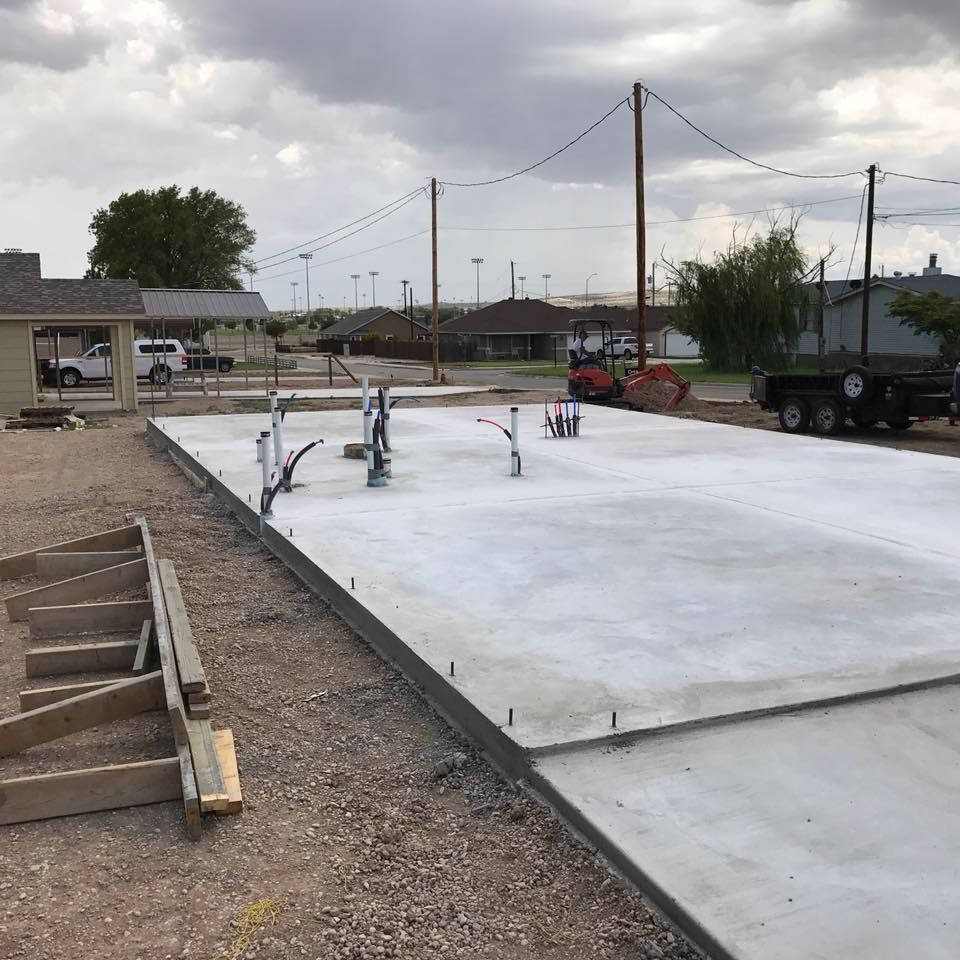 A large concrete slab is being built on a dirt road