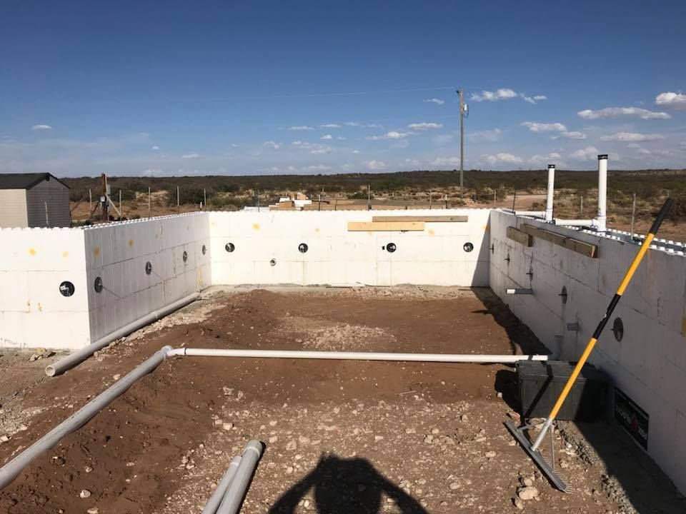 A shadow of a person is cast on the ground in front of a building under construction.