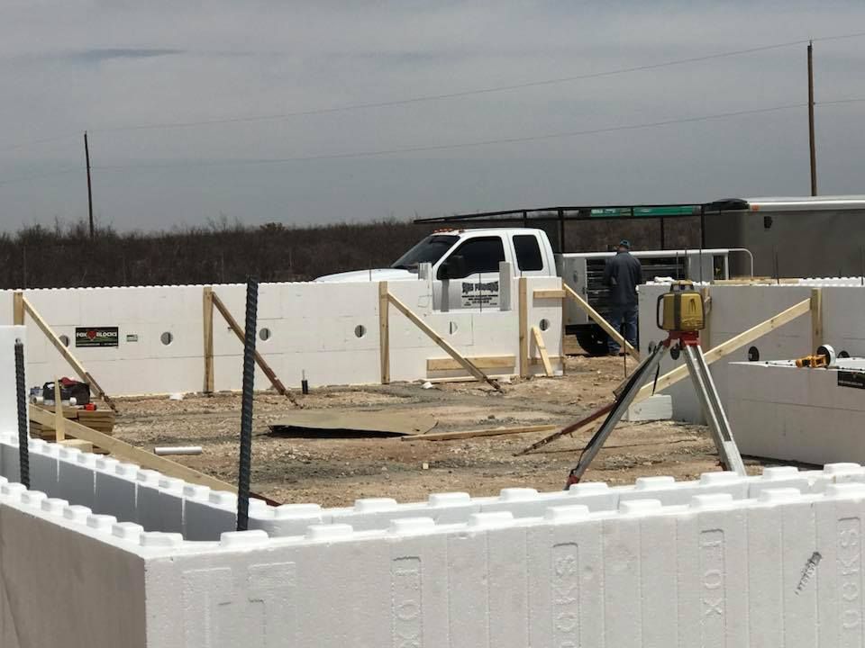 A white truck is parked in front of a building under construction