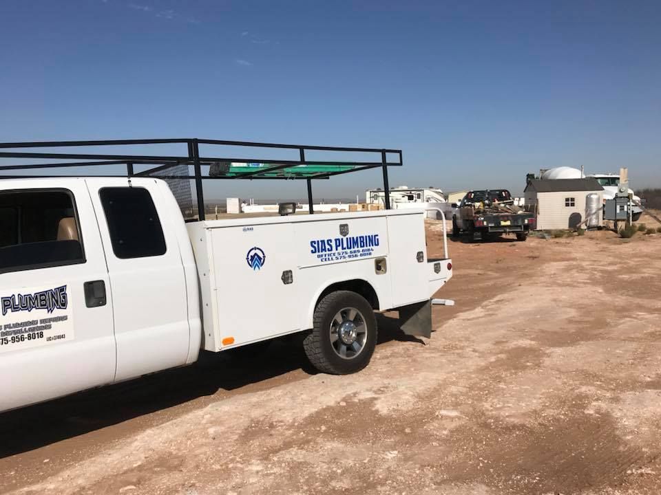 A white utility truck is parked in a dirt field.