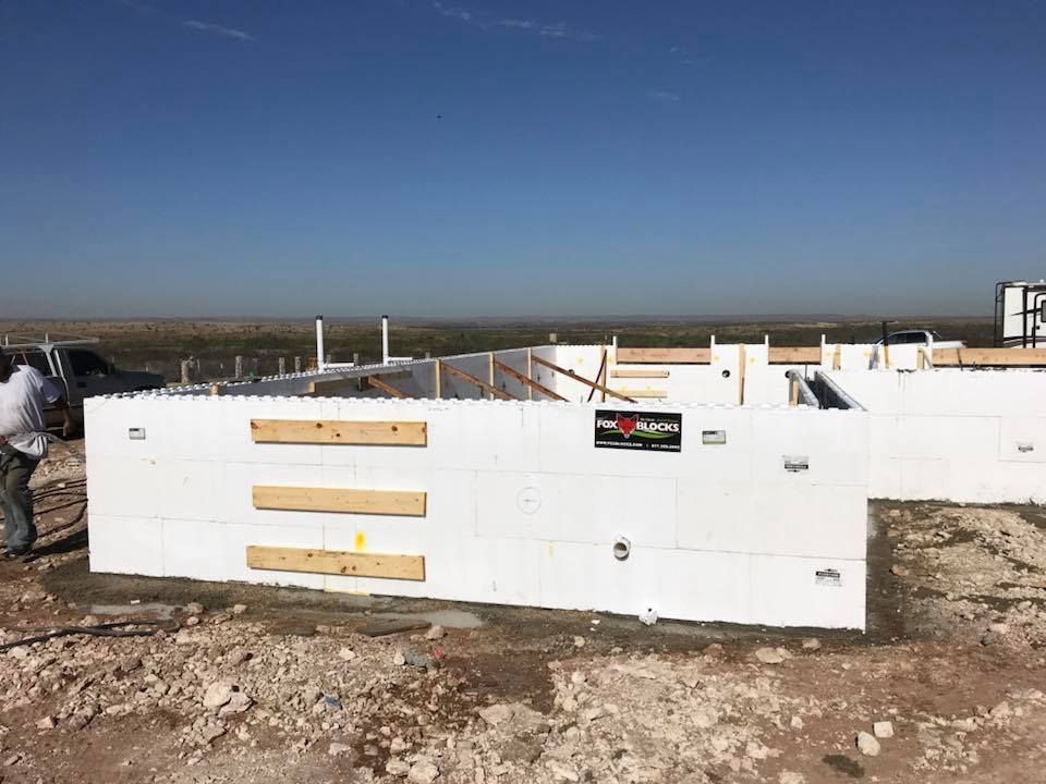 A man is standing next to a wall made of styrofoam blocks.