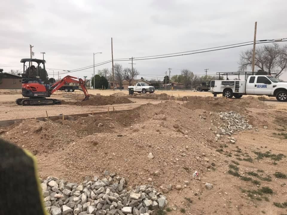 An excavator is digging a hole in a dirt field next to a truck.