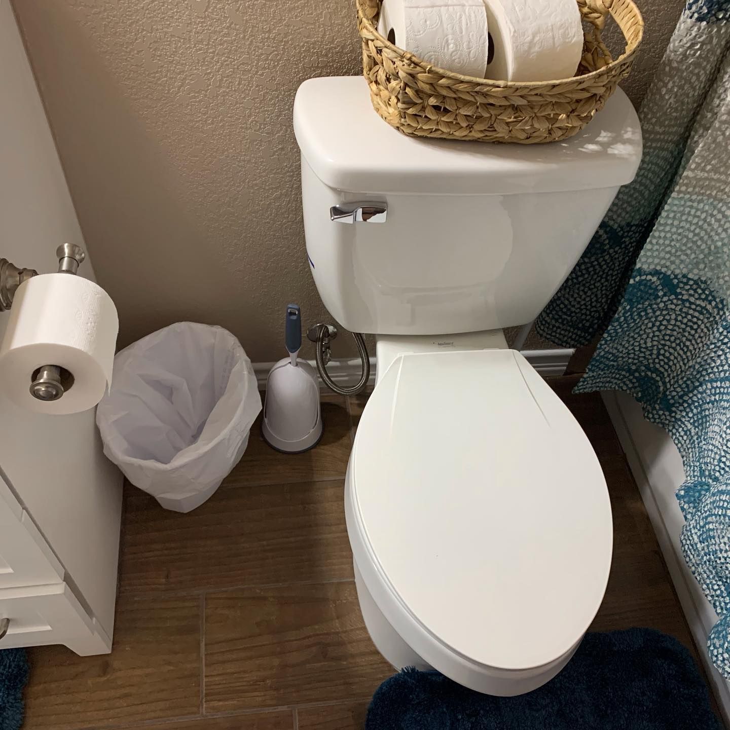 A toilet with a basket of toilet paper on top of it in a bathroom.