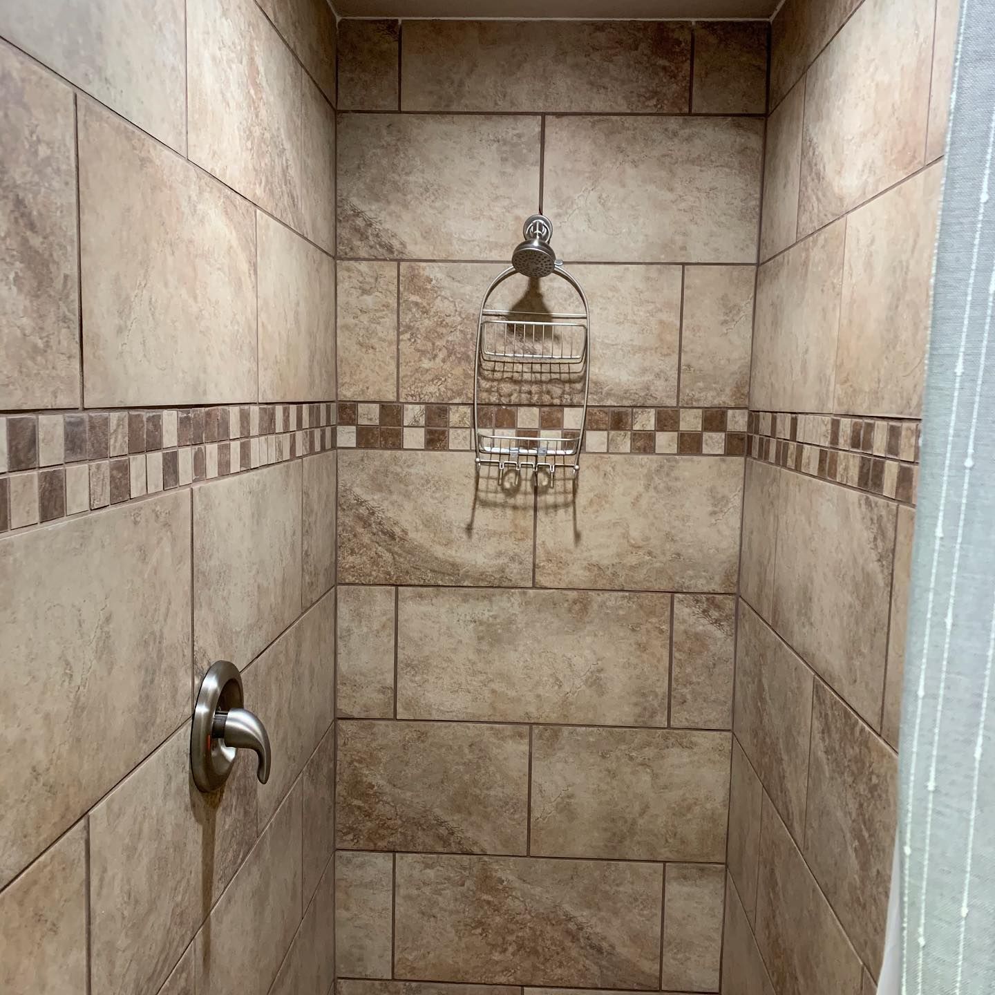 A shower stall with tiled walls and a shower head
