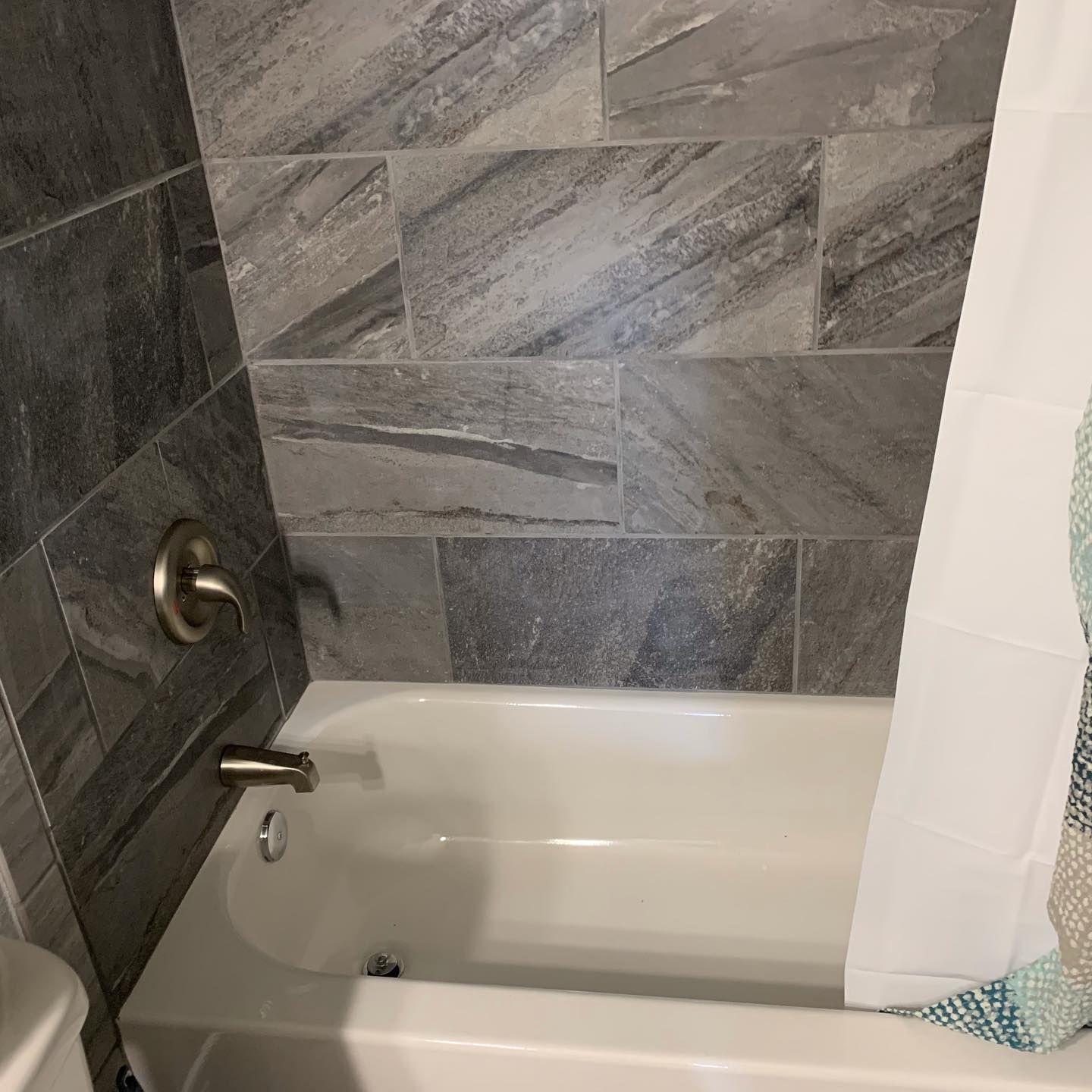 There is a bathtub in the bathroom next to a toilet.