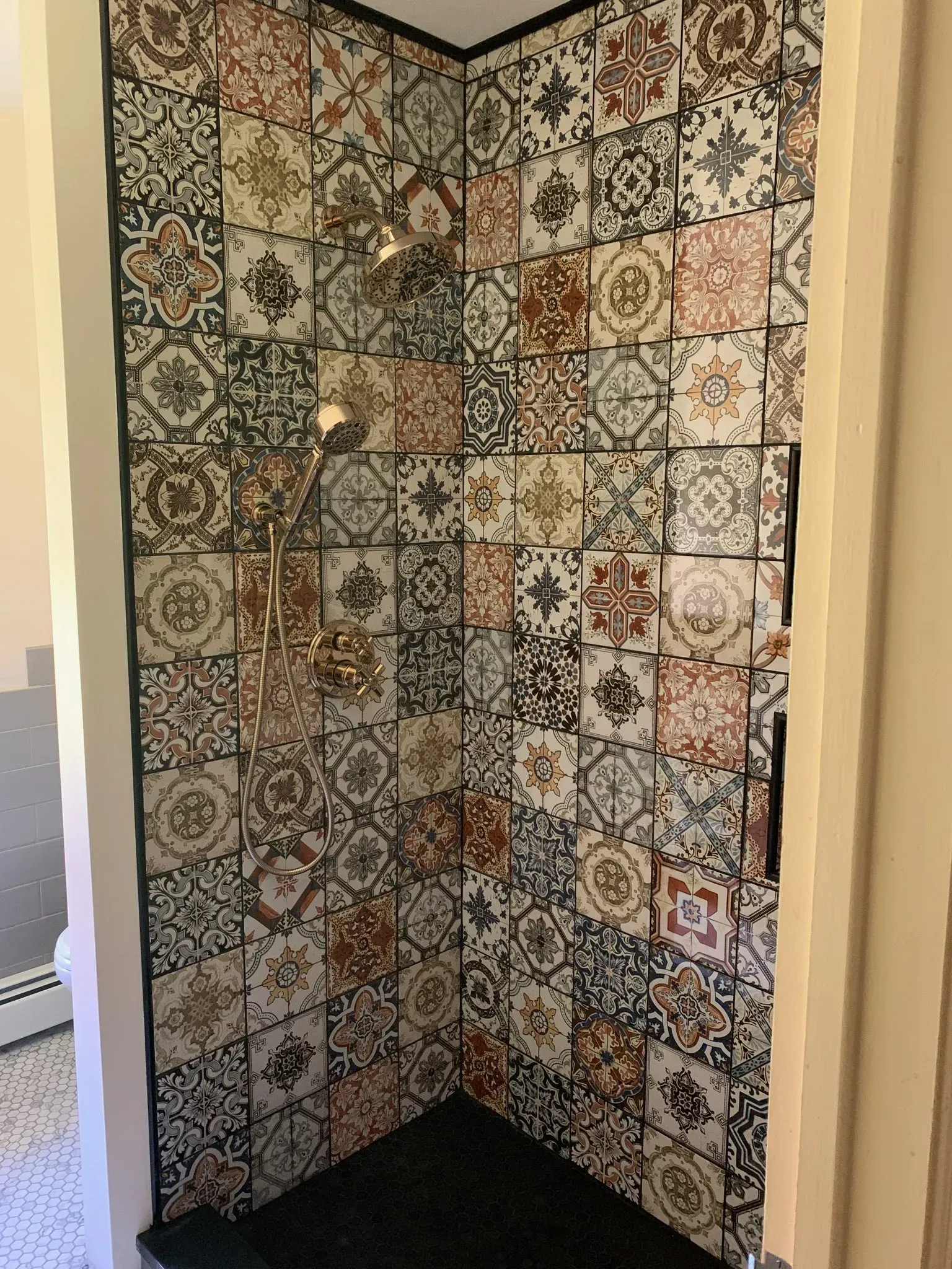 A shower stall with a lot of tiles on the wall.