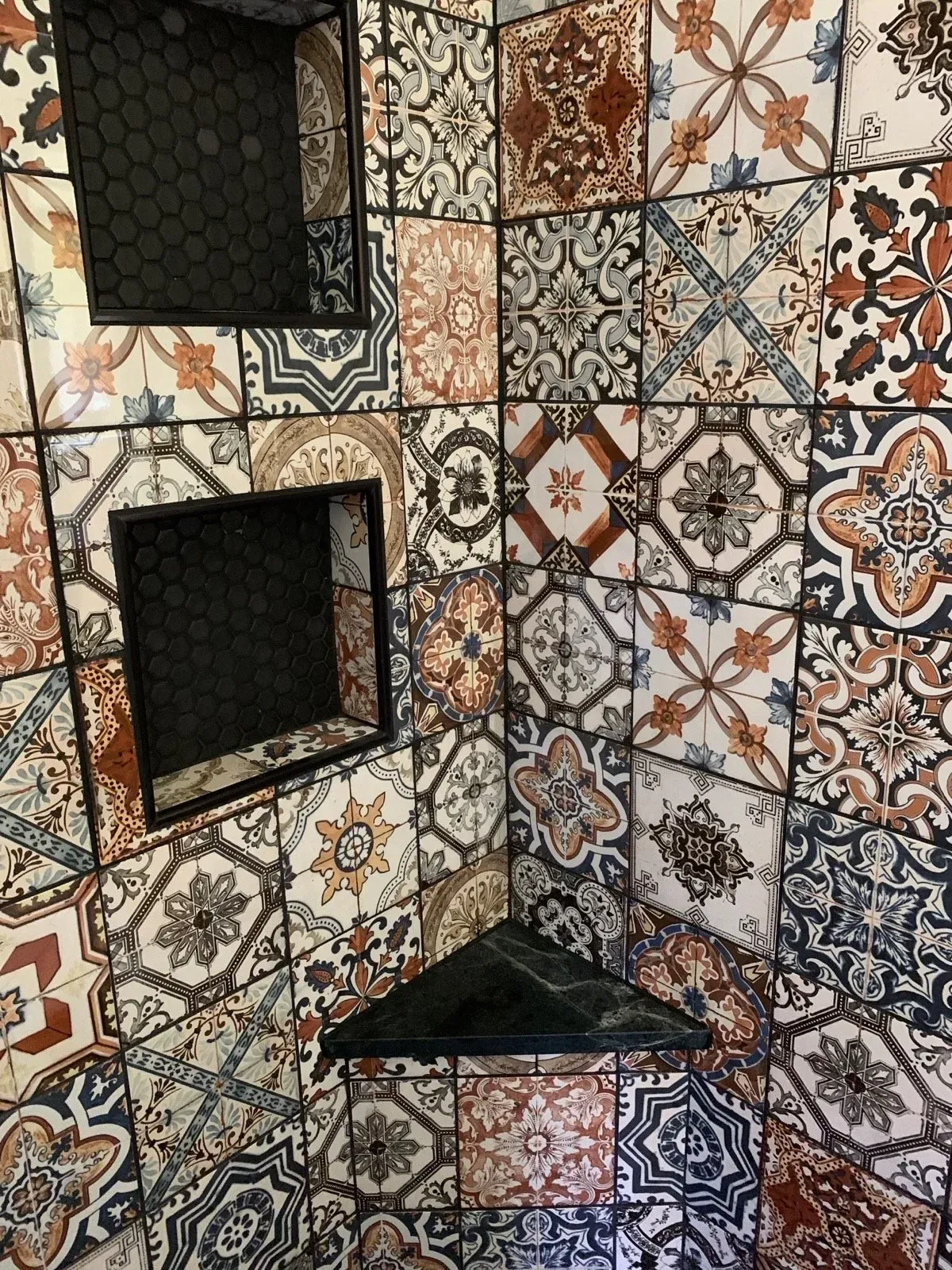 A bathroom with a lot of tiles on the wall and a shower stall.