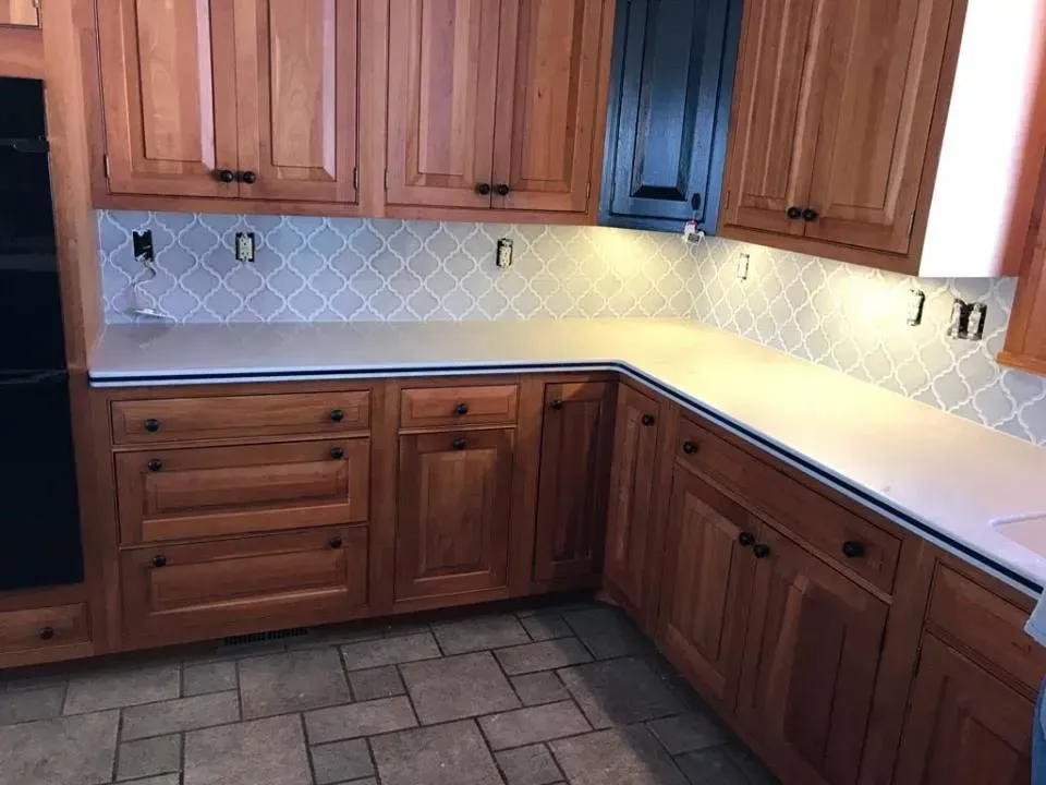 A kitchen with wooden cabinets and white counter tops.