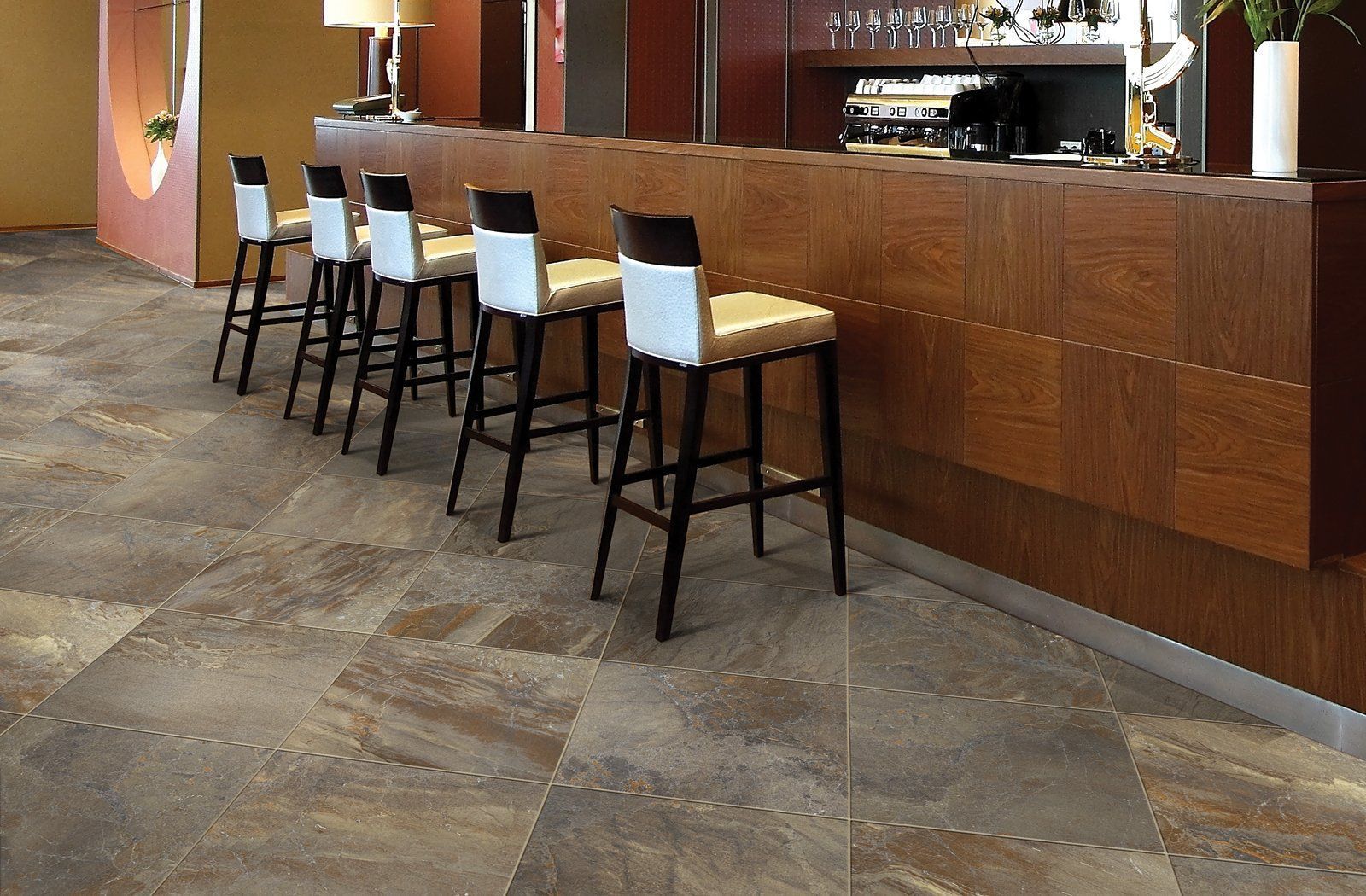 A row of bar stools are lined up in front of a wooden counter.
