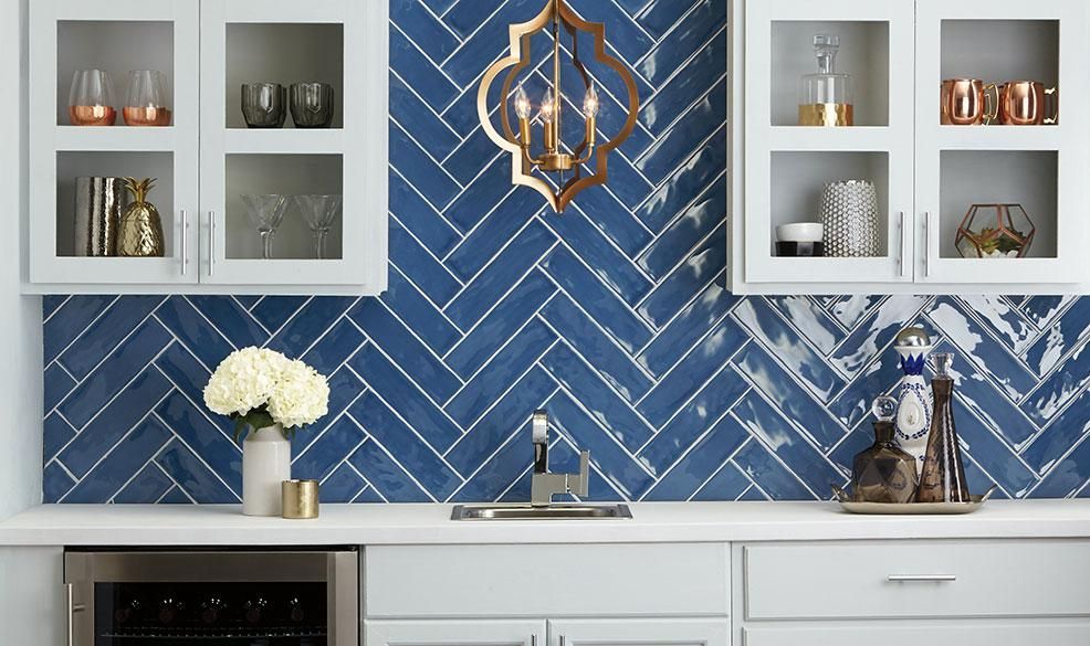 A kitchen with blue tiles on the wall and white cabinets.