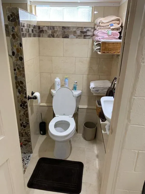 A bathroom with a toilet , sink , and window.