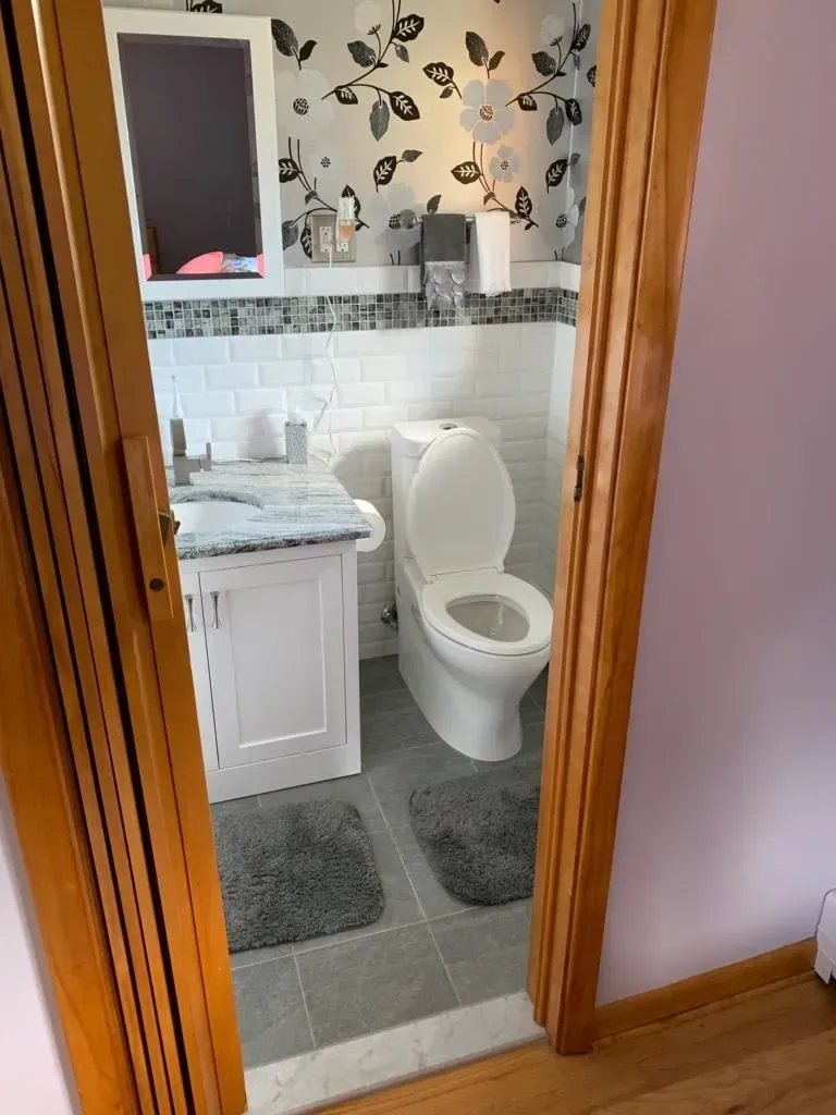 A bathroom with a toilet , sink and mirror.