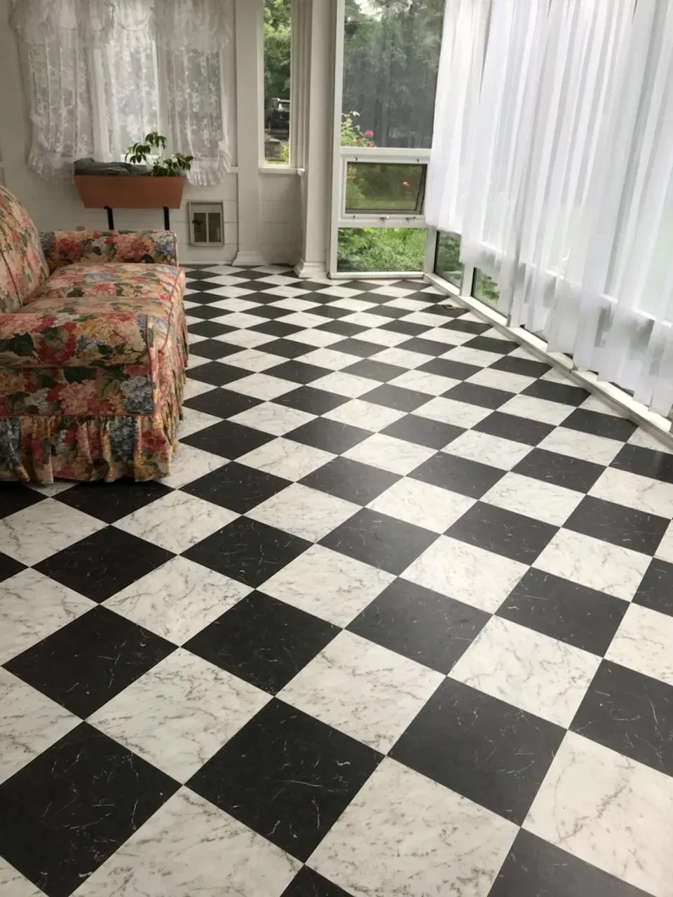 A living room with a black and white checkered floor and a couch.