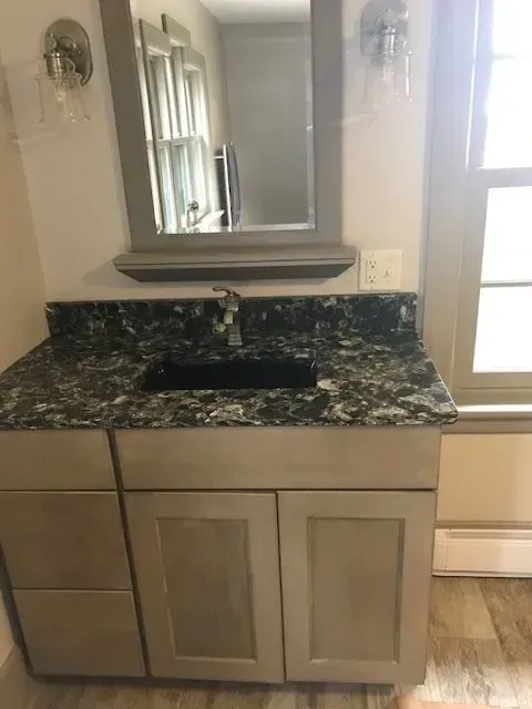 A bathroom with a sink , toilet , and window.