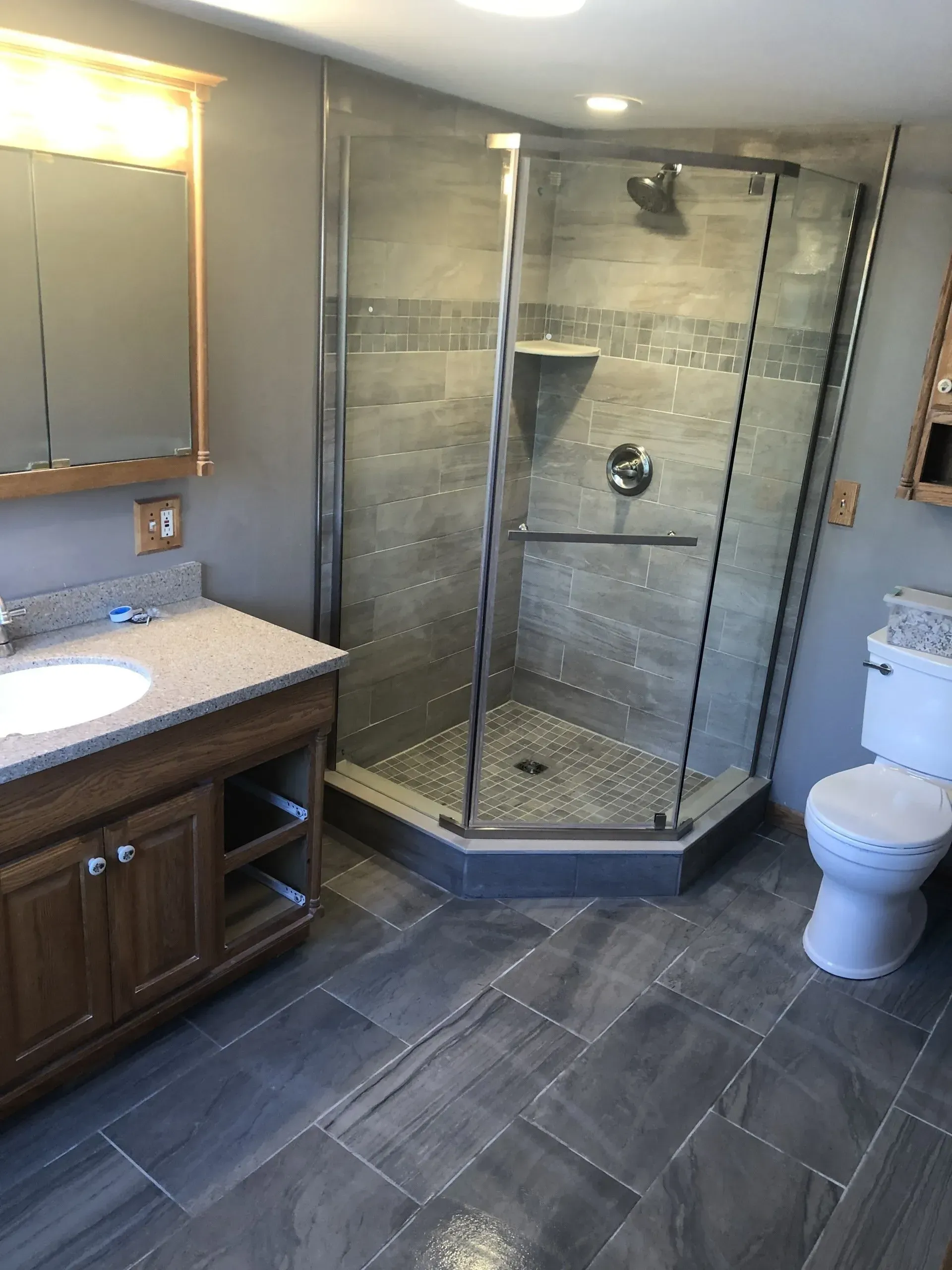 A bathroom with a toilet , sink , shower and mirror.