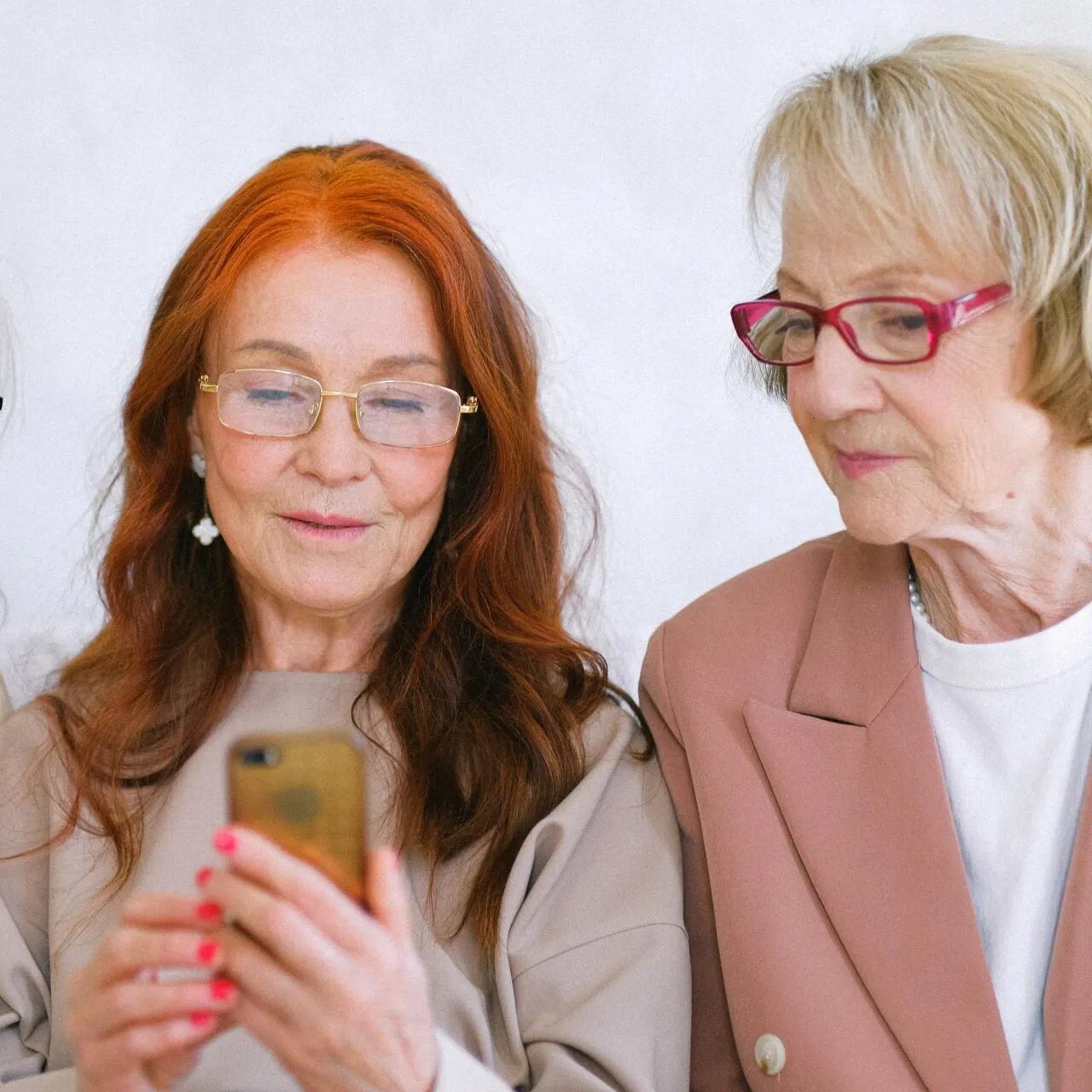 Two older women are looking at a cell phone together.