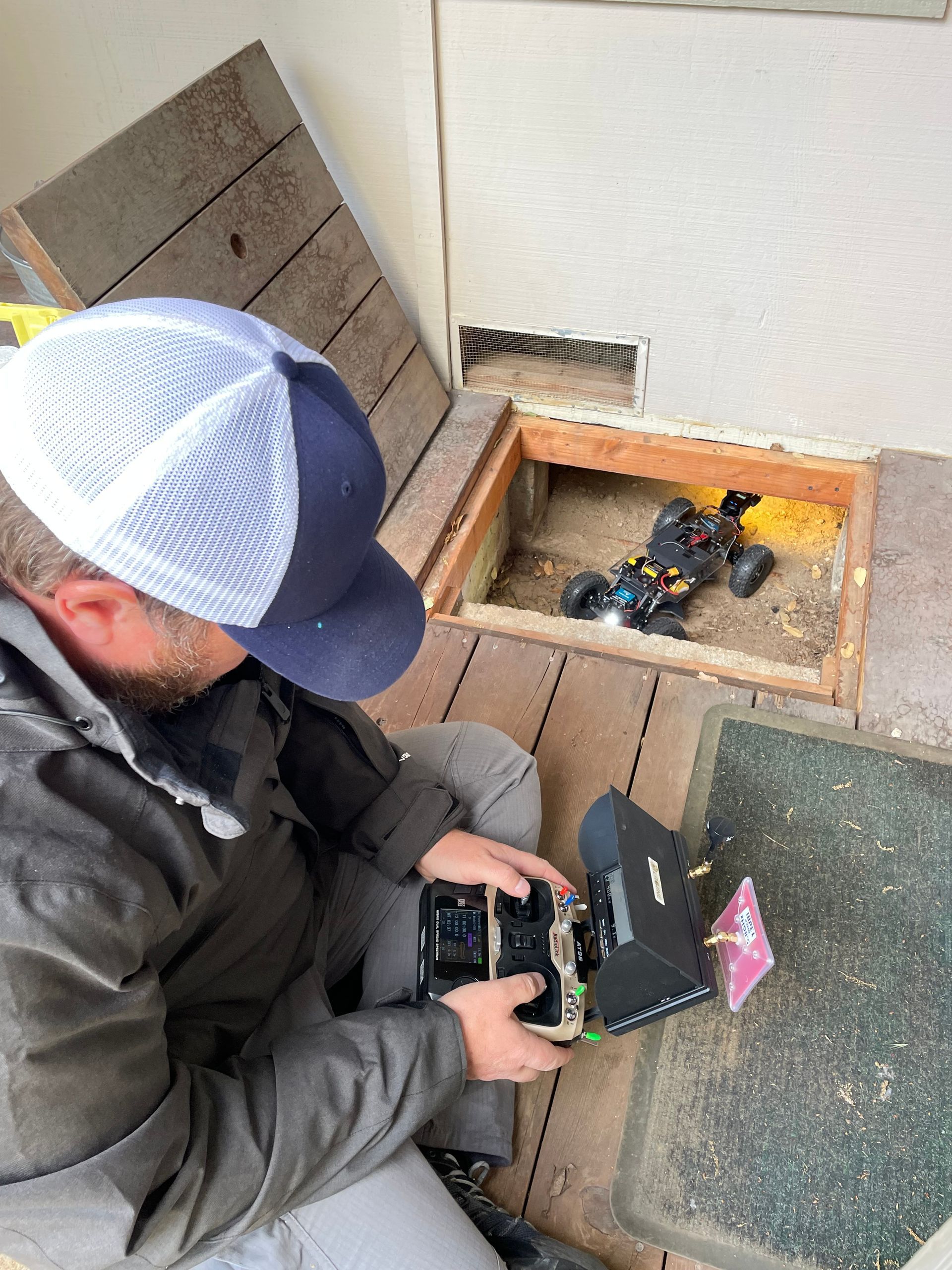 A man is sitting on a porch playing with a remote control car.